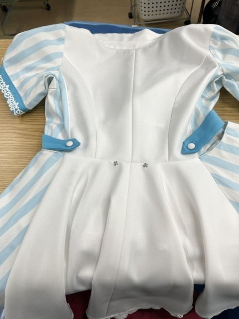 白地にブルーのラインがアクセントとして使われている飲食店の制服ワンピースを洗濯した際、ボールペンが一緒に入っていて広範囲にインクシミが付いてしまった染み抜きクリーニング事例(９，９００円税込）2026.10.15