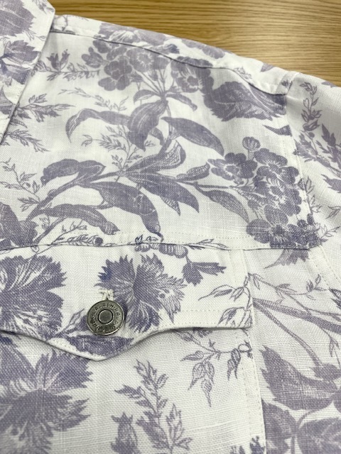 ローレンラルフローレンの白地に紫の花柄があしらわれたデニムジャケットの背面裾の革パッチからの色移りがキレイに落ちた染み抜きクリーニング事例（７，７００円税込、修理代も含む）2026.04.11