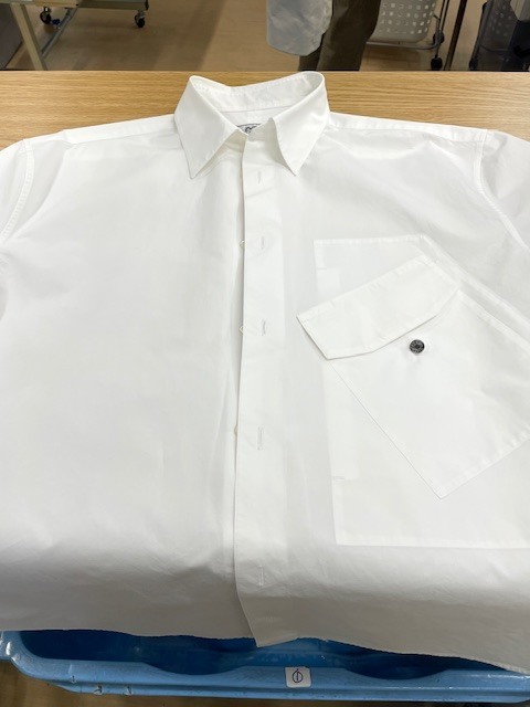 家庭洗濯時に左胸ポケットに付いていた取り外し可能な焦げ茶色の革を外し忘れそこから各所に濃く色滲みしてしまった白いエルメスコットンシャツ染み抜きクリーニング事例(５，５００円税込)2026.05.17