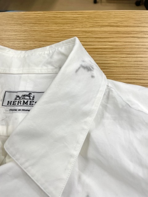 家庭洗濯時に左胸ポケットに付いていた取り外し可能な焦げ茶色の革を外し忘れそこから各所に濃く色滲みしてしまった白いエルメスコットンシャツ染み抜きクリーニング事例(５，５００円税込)2026.05.17